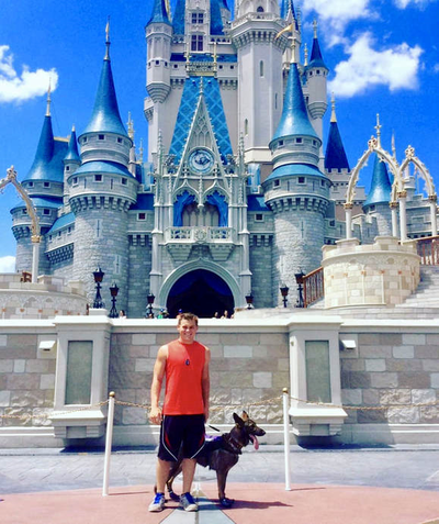 A Limitless K9 service dog and his teenage handler at Disney World in front of Cinderella's Castle